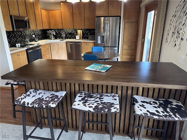 kitchen featuring stainless steel appliances, light countertops, a sink, and decorative backsplash