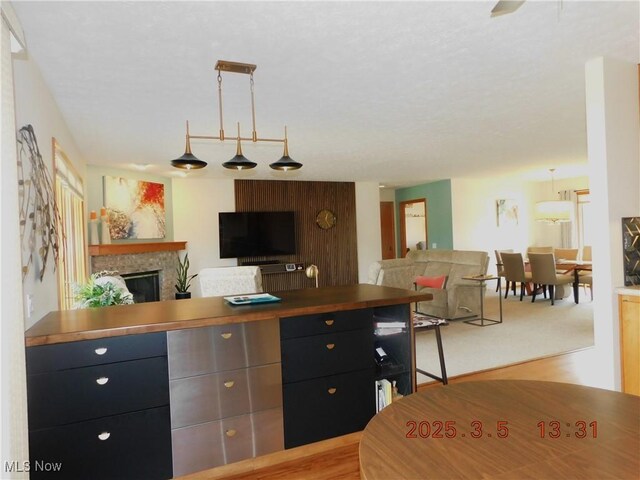 kitchen featuring a fireplace, open floor plan, dark cabinets, and decorative light fixtures