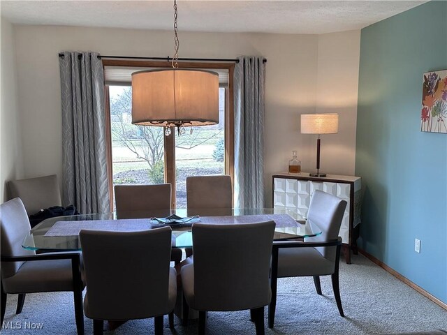 carpeted dining room with baseboards