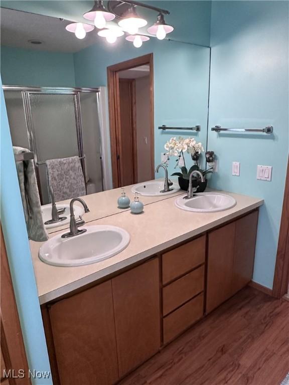 full bathroom with a stall shower, a sink, and wood finished floors