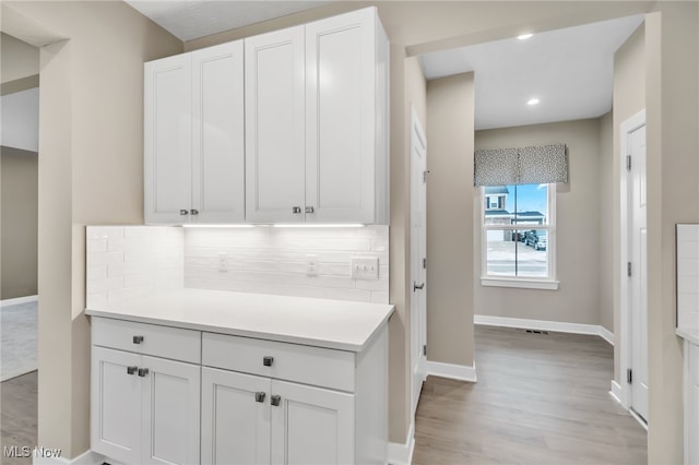 kitchen with baseboards, light countertops, white cabinetry, and decorative backsplash