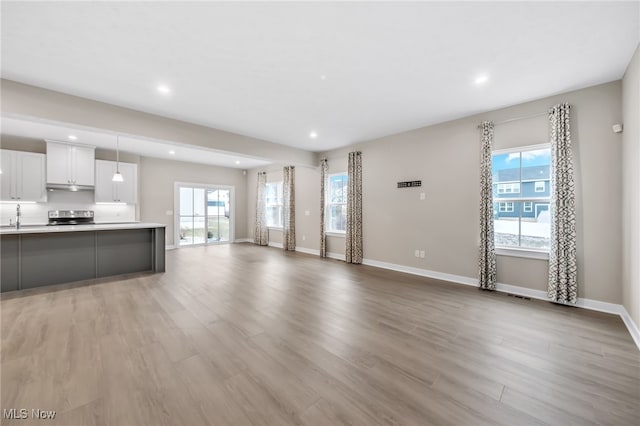 unfurnished living room featuring light wood finished floors, baseboards, and recessed lighting