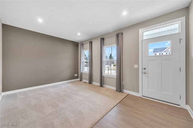 entryway with light carpet, light wood-style floors, recessed lighting, and baseboards