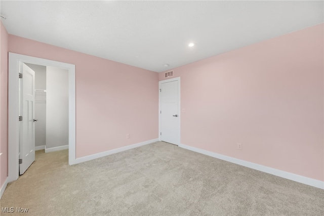 empty room with baseboards, visible vents, and light colored carpet