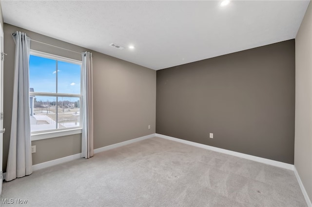 empty room with visible vents, light carpet, and baseboards