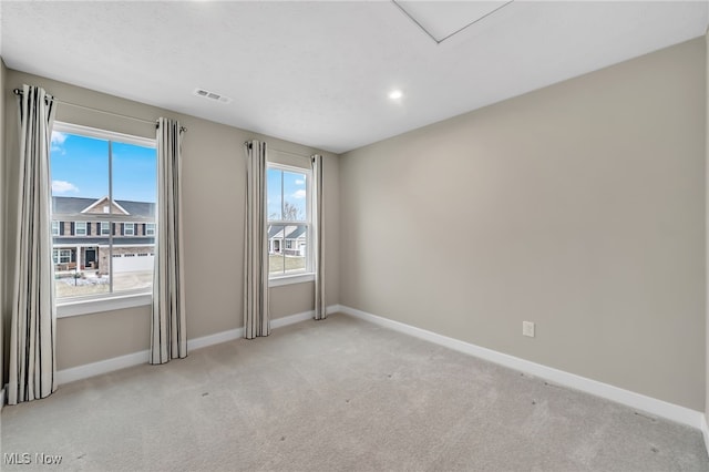 carpeted spare room with visible vents and baseboards