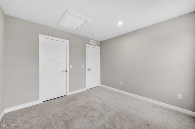 unfurnished room with carpet floors, attic access, visible vents, and baseboards