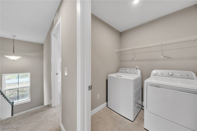 clothes washing area featuring light tile patterned floors, light colored carpet, washer and dryer, laundry area, and baseboards