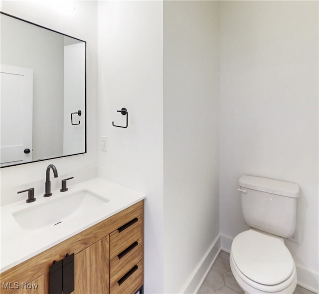 half bathroom with toilet, tile patterned flooring, baseboards, and vanity