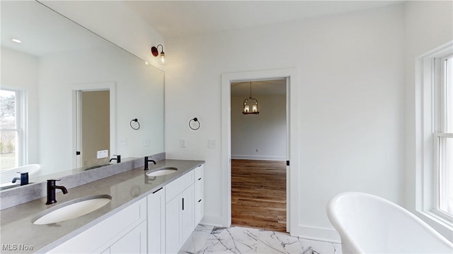 full bathroom with a soaking tub, marble finish floor, a sink, and double vanity