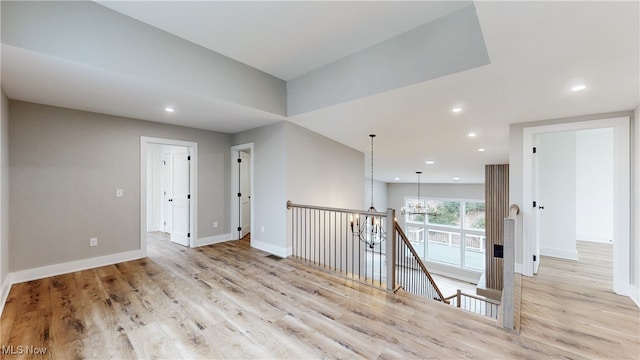 unfurnished room with baseboards, recessed lighting, light wood-type flooring, and a notable chandelier