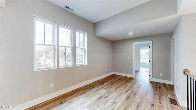 unfurnished room featuring light wood-style floors, visible vents, and baseboards