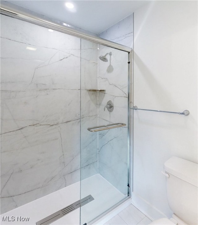 full bathroom featuring toilet and a marble finish shower