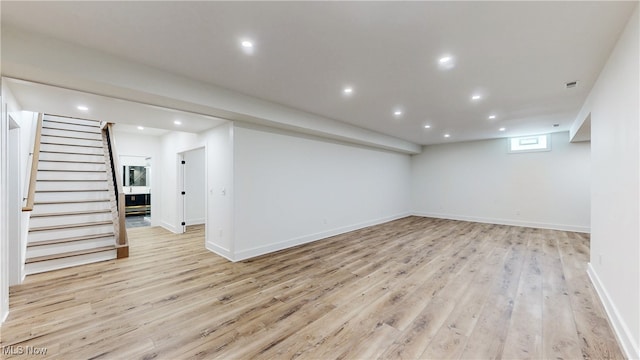 below grade area with recessed lighting, stairway, and light wood finished floors