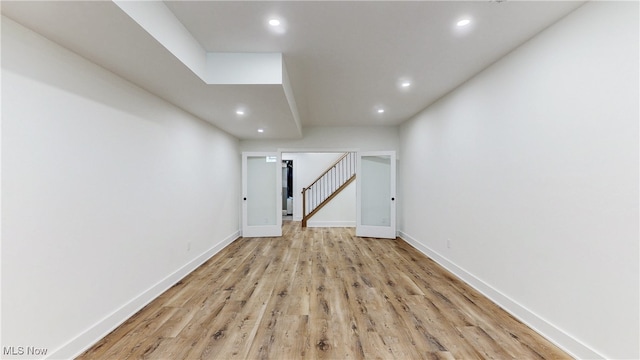 spare room with light wood finished floors, stairway, recessed lighting, and baseboards