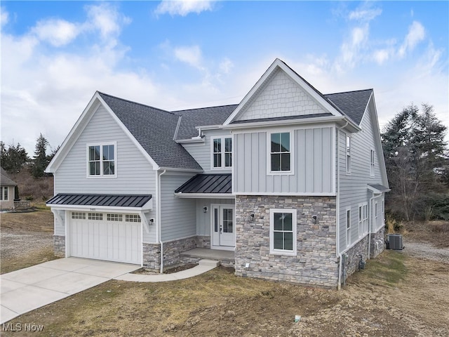 view of front facade with an attached garage, cooling unit, a shingled roof, driveway, and a standing seam roof