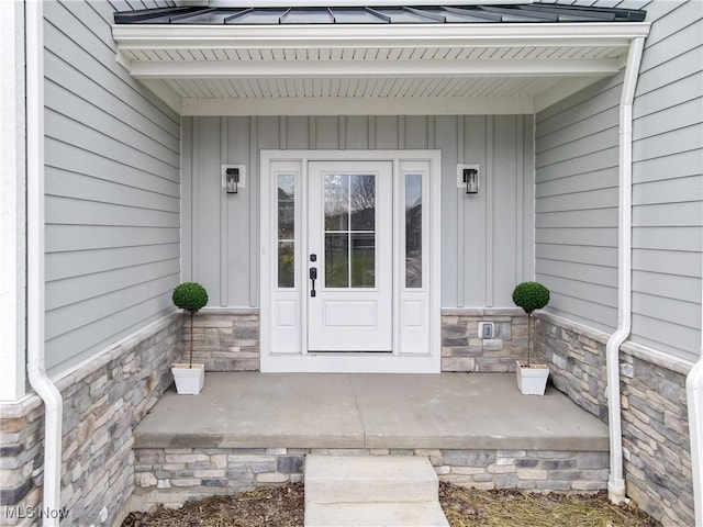 view of exterior entry with stone siding and a porch