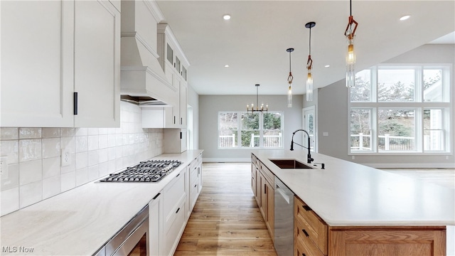 kitchen with stainless steel appliances, a sink, light wood-style floors, tasteful backsplash, and custom range hood