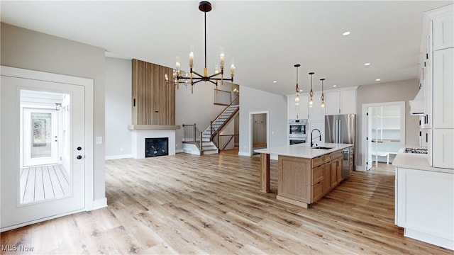 kitchen featuring appliances with stainless steel finishes, light countertops, light wood-type flooring, a fireplace, and a sink