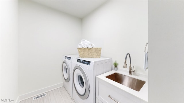 laundry room featuring cabinet space, baseboards, visible vents, independent washer and dryer, and a sink