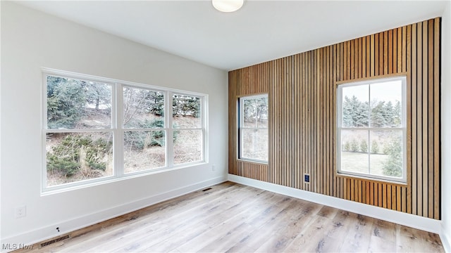 spare room featuring light wood-type flooring, visible vents, and baseboards