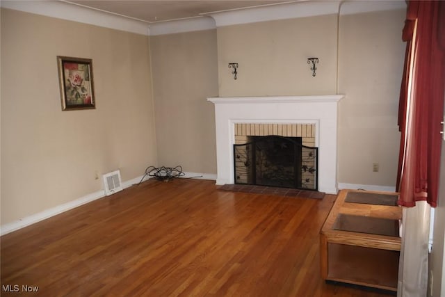 living area with a fireplace, wood finished floors, visible vents, and baseboards