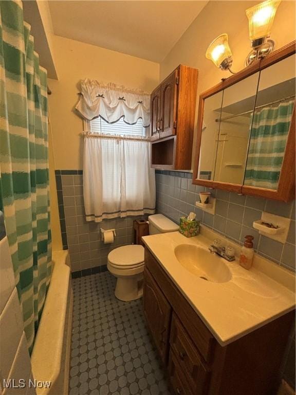 bathroom featuring wainscoting, toilet, shower / tub combo with curtain, vanity, and tile walls