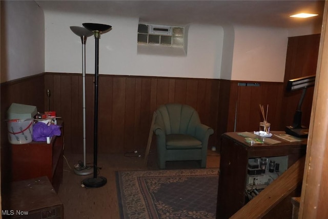 sitting room featuring an AC wall unit, wainscoting, and wood walls