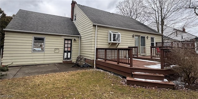 back of house with a yard, a shingled roof, a chimney, and a wooden deck