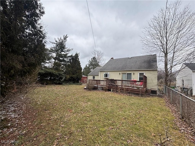 back of property featuring fence, a lawn, and a wooden deck