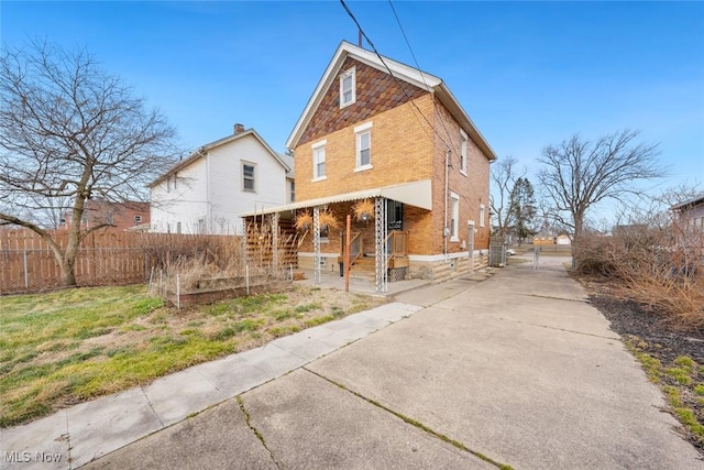 back of property with a garden, a gate, brick siding, and fence