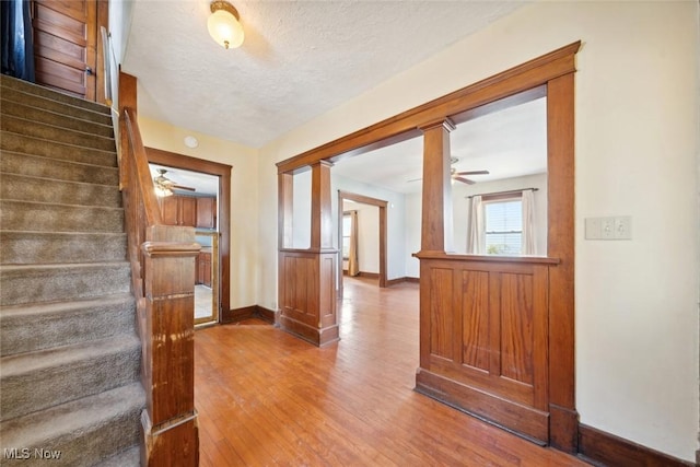 corridor featuring a textured ceiling, stairway, wood finished floors, and baseboards