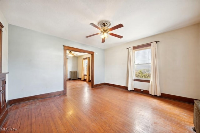 unfurnished room featuring baseboards, ceiling fan, light wood-style flooring, and radiator