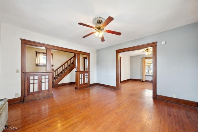 unfurnished living room with light wood-style flooring, stairway, and baseboards