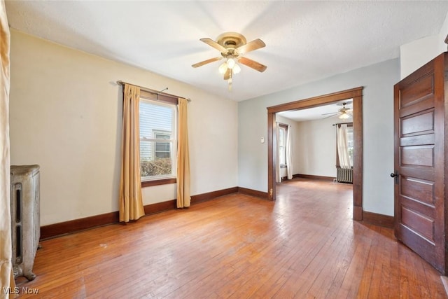 unfurnished living room featuring baseboards, light wood finished floors, and radiator