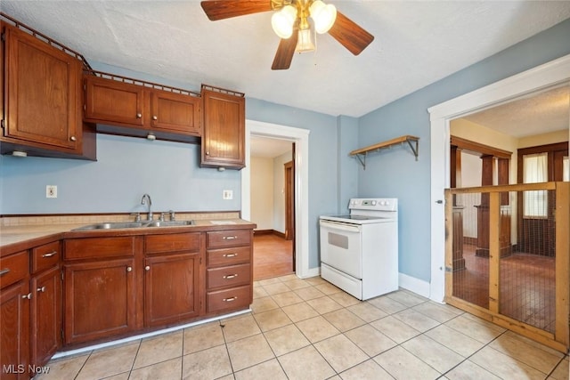 kitchen featuring brown cabinetry, white range with electric stovetop, light countertops, and a sink