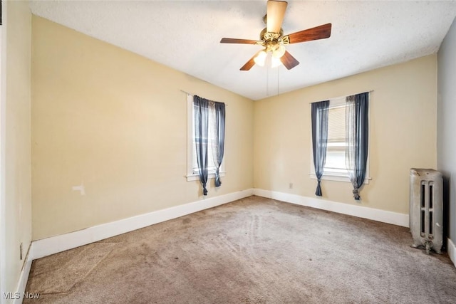 carpeted spare room featuring radiator heating unit, baseboards, and ceiling fan