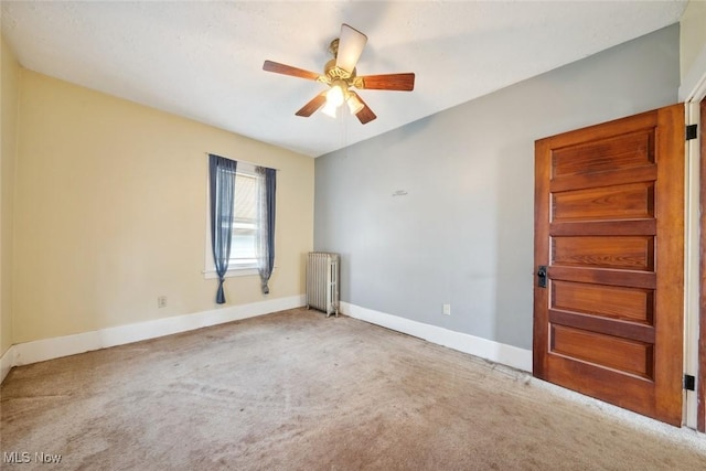 spare room featuring ceiling fan, radiator heating unit, carpet, and baseboards