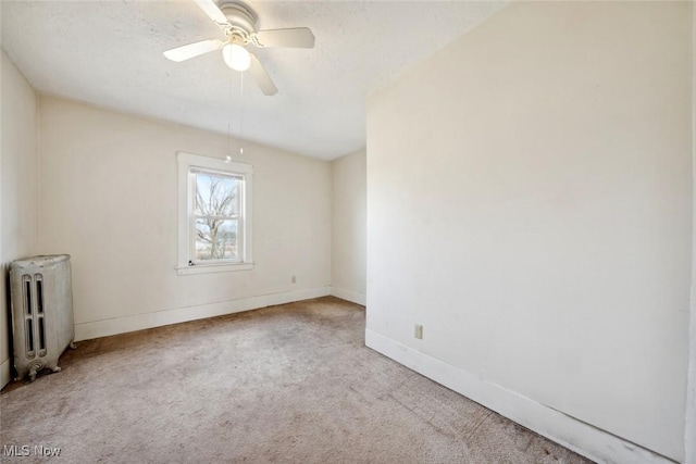 spare room featuring radiator, carpet, baseboards, and a ceiling fan