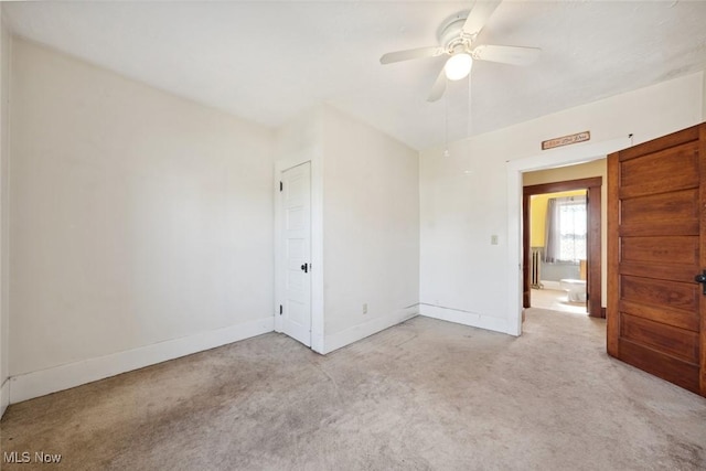 unfurnished room featuring a ceiling fan, light colored carpet, and baseboards