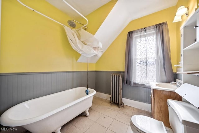 bathroom featuring toilet, a wainscoted wall, vanity, a freestanding bath, and radiator