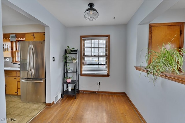 dining space with light wood-type flooring, visible vents, and baseboards