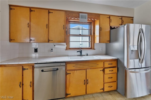 kitchen featuring stainless steel appliances, light countertops, a sink, and tasteful backsplash