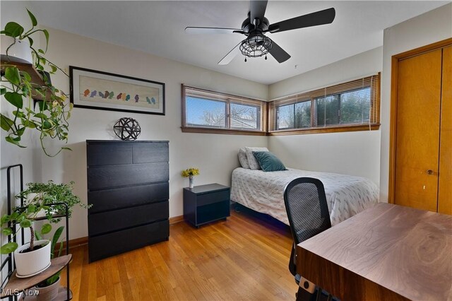 bedroom with a ceiling fan, baseboards, and light wood finished floors