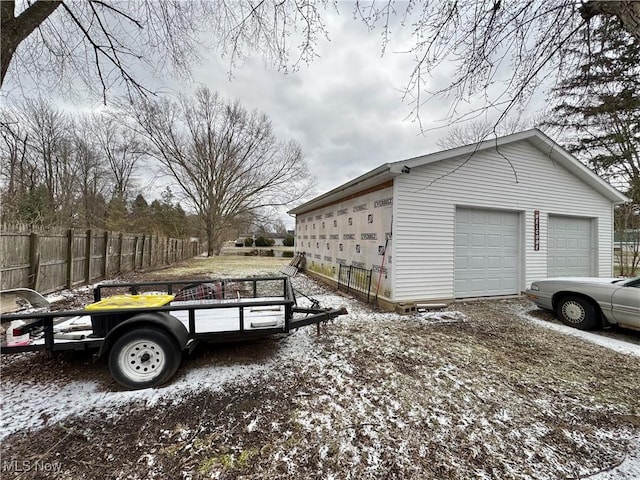 view of side of property with a garage, an outbuilding, and fence