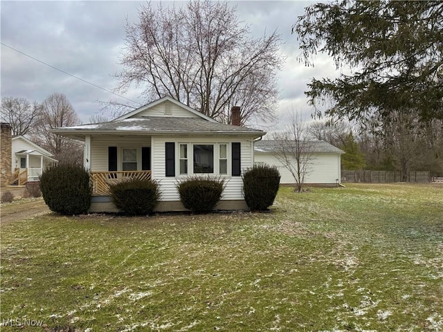 view of front of home with a chimney, a front lawn, a porch, and fence