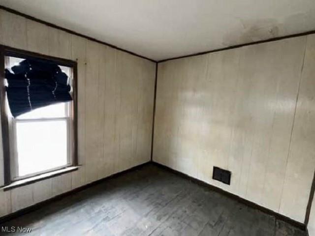 unfurnished room featuring wooden walls and wood finished floors