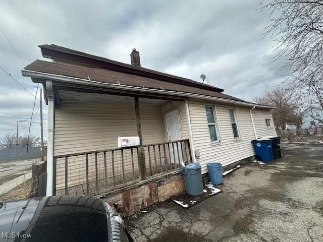 rear view of house featuring covered porch and a chimney