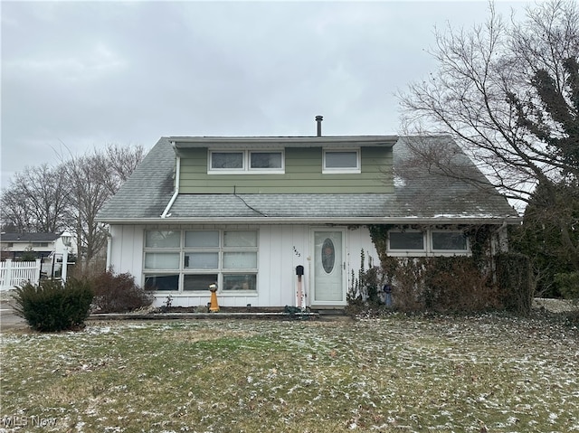 bungalow with roof with shingles, a front yard, board and batten siding, and fence