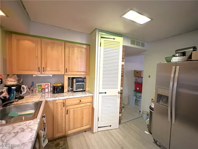 kitchen featuring light countertops, stainless steel fridge, a sink, and light brown cabinets